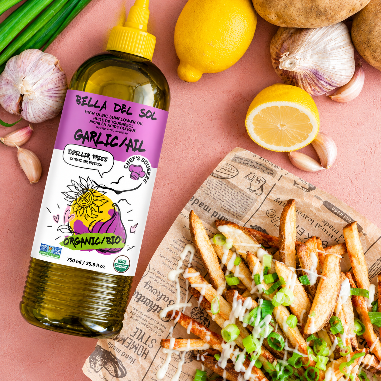 
                  
                    A bottle of Bella del Sol Garlic Aioli organic oil is styled on a pink surface with lemons, garlic, green onions, and loaded fries on a newspaper-lined plate.
                  
                