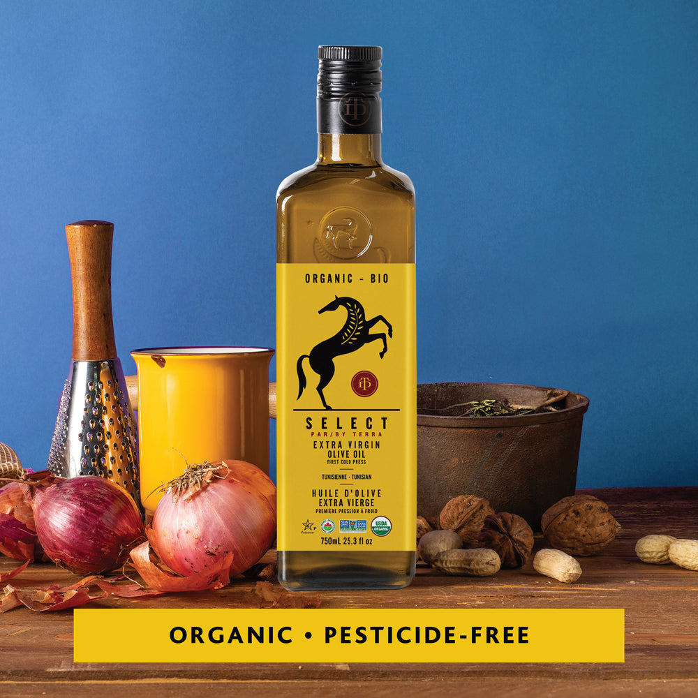 Select by Terra Organic Extra Virgin Olive Oil 750ml bottle with kitchen tools, onions, nuts, and spices on a wooden table – organic and pesticide-free olive oil