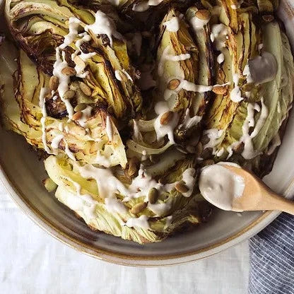 
                  
                    Quartiers de chou rôtis avec tahini à l'ail et graines de citrouille grillées 
                  
                